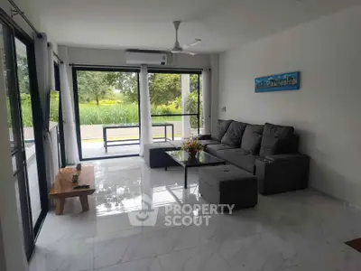 Spacious living room with modern furniture and large windows offering a serene garden view.
