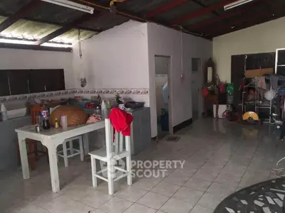 Spacious kitchen area with tiled flooring and rustic decor, featuring a dining table and ample storage space.