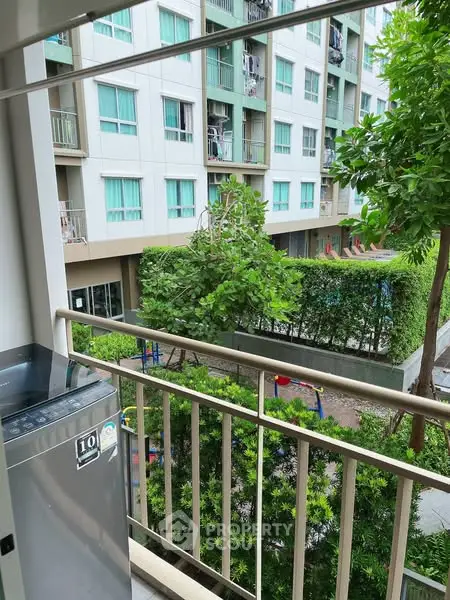 Charming balcony view overlooking lush garden in modern apartment complex.