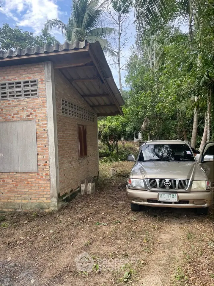 Charming rustic brick house with lush greenery and a parked car, perfect for nature lovers seeking tranquility.