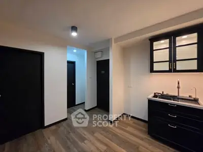 Modern kitchen with sleek black cabinets and wood flooring in a contemporary apartment.