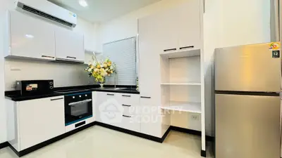 Modern kitchen with sleek cabinets, stainless steel fridge, and built-in oven in a stylish apartment.