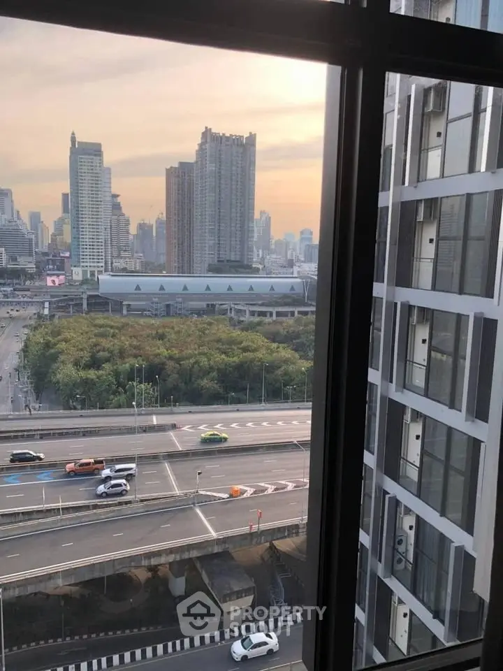 Stunning cityscape view from high-rise apartment window overlooking urban skyline and highway.