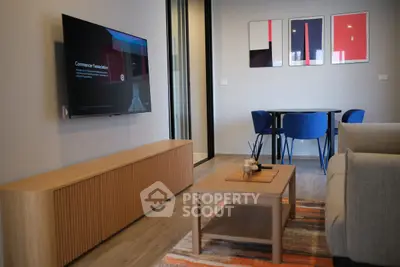 Modern living room with stylish furniture and wall art, featuring a mounted TV and cozy seating area.