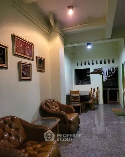 Cozy living area with wicker chairs and wall art, leading to a dining space and kitchen.