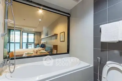 Modern bathroom with bathtub and view into a stylish bedroom