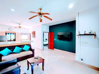 Spacious living room with modern decor and open layout, featuring ceiling fans and a wall-mounted TV.