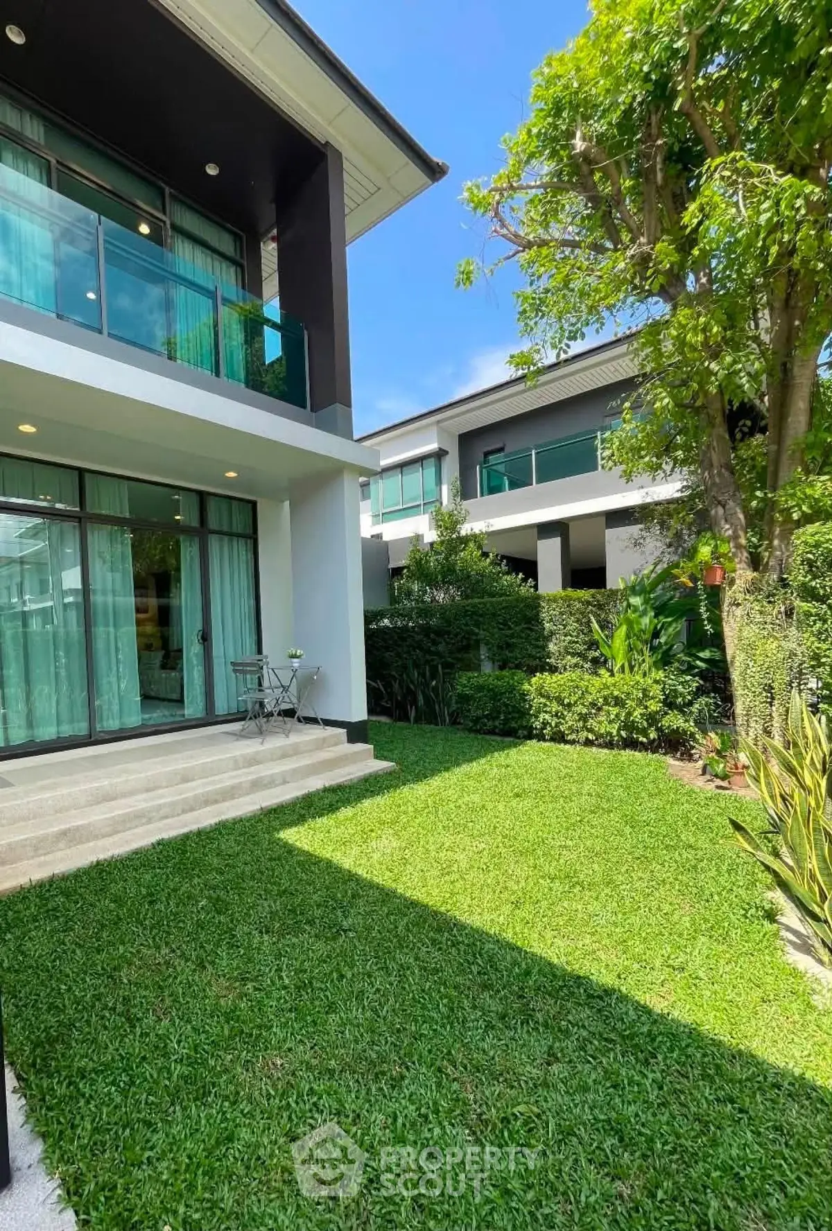Modern two-story house with lush garden and large windows, perfect for family living.