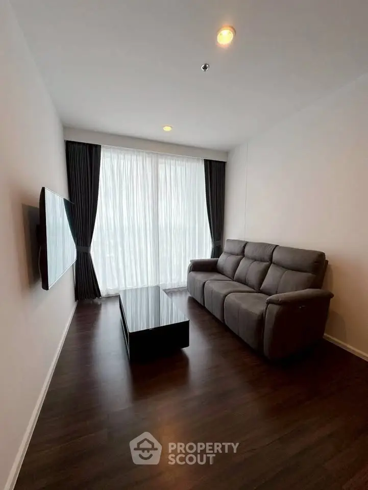 Modern living room with sleek dark flooring, plush sofa, and wall-mounted TV, perfect for relaxation.