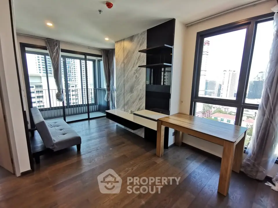 Modern living room with large windows and city view, featuring wooden floors and stylish decor.