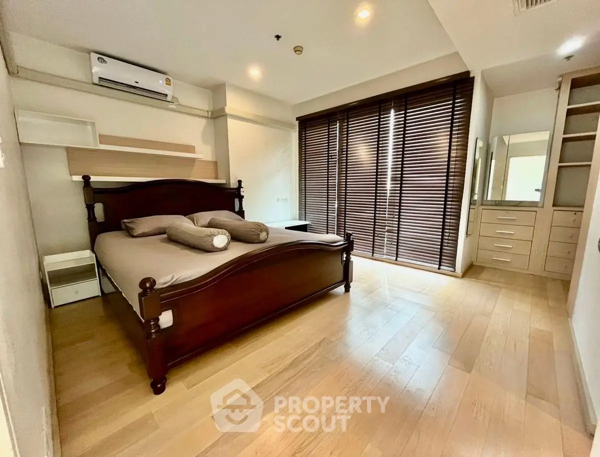 Spacious bedroom with wooden flooring and large windows in modern apartment