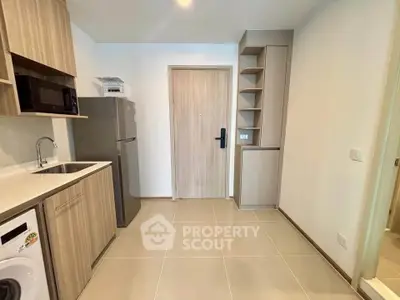 Modern kitchen with sleek cabinetry, stainless steel appliances, and washing machine in compact layout.