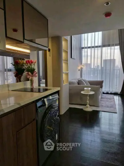 Modern living room with city view, cozy sofa, and stylish kitchen area.