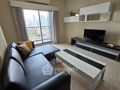 Modern living room with city view, featuring sleek black sofa and stylish entertainment unit.