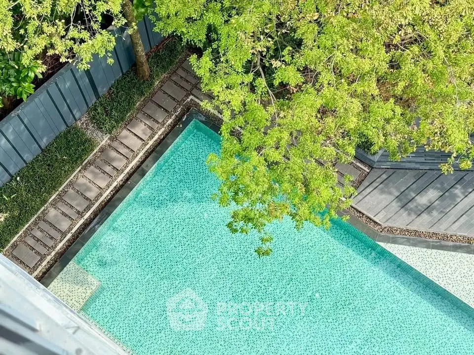 Stunning aerial view of a serene outdoor pool surrounded by lush greenery, perfect for relaxation.