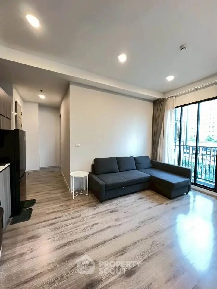 Spacious modern living room with large windows and sleek wooden flooring.