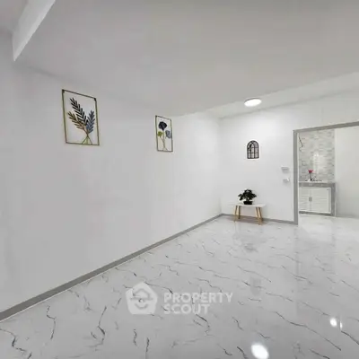 Spacious modern interior with marble flooring and minimalist decor, leading to a stylish kitchen.