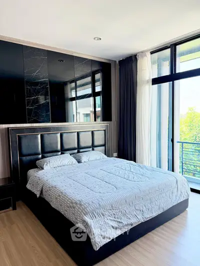 Luxurious bedroom with modern decor and large windows offering natural light and balcony access.