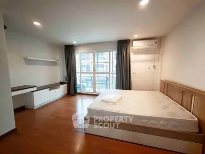 Spacious bedroom with modern furnishings and large window offering natural light.