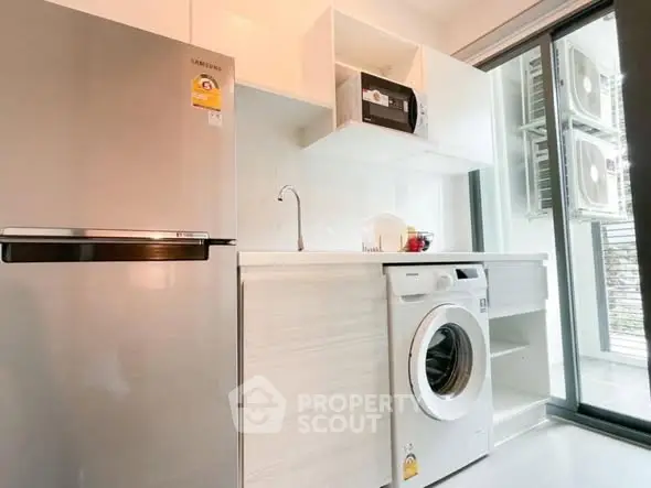 Modern kitchen with sleek appliances and washing machine in bright interior.