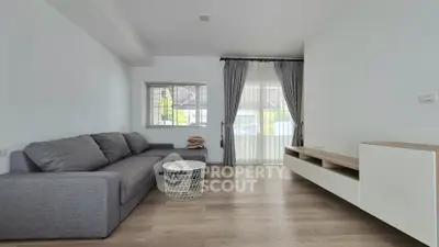 Modern living room with gray sofa, stylish coffee table, and large window with curtains.