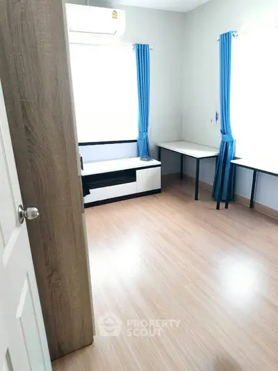 Bright study room with blue curtains and wooden flooring