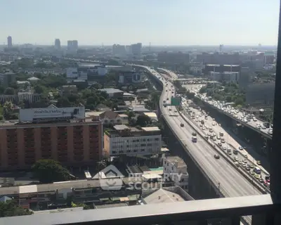 Stunning cityscape view from high-rise balcony overlooking busy highway and urban skyline.