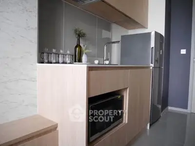 Modern compact kitchen with sleek cabinetry and stainless steel appliances in a stylish apartment.