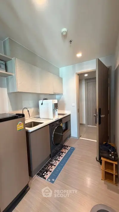 Modern kitchen with sleek cabinetry, compact appliances, and stylish flooring in a contemporary apartment.