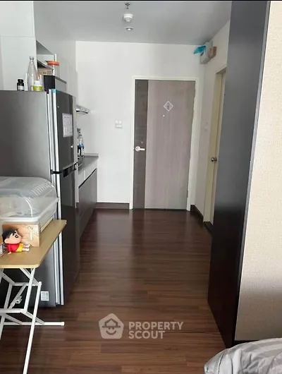 Modern kitchen with sleek appliances and wooden flooring in a cozy apartment.