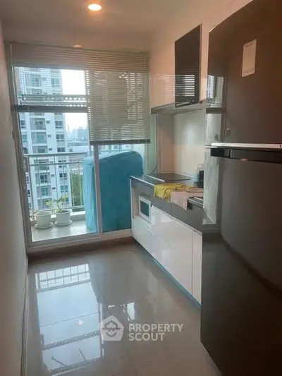 Modern kitchen with sleek appliances and balcony view in high-rise apartment.