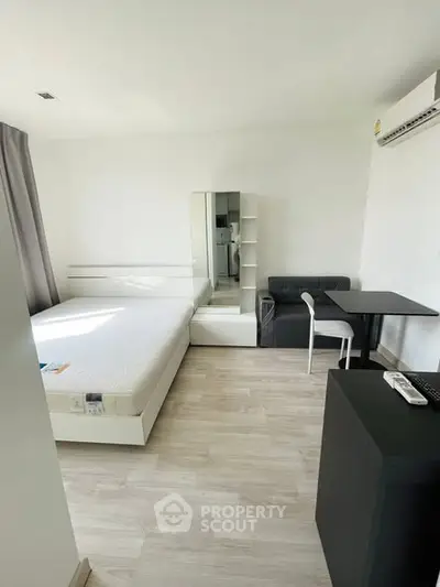 Modern studio apartment with minimalist design, featuring a cozy bed, compact dining area, and sleek furnishings.