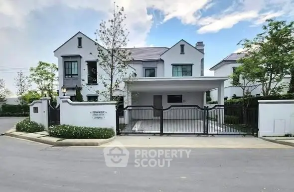 Elegant modern house with gated entrance and lush greenery in a serene neighborhood.