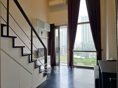 Modern loft apartment with large windows and city view, featuring sleek staircase and elegant decor.