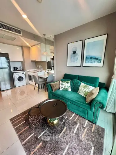 Modern living room with green sofa, stylish decor, and open kitchen layout in a contemporary apartment.