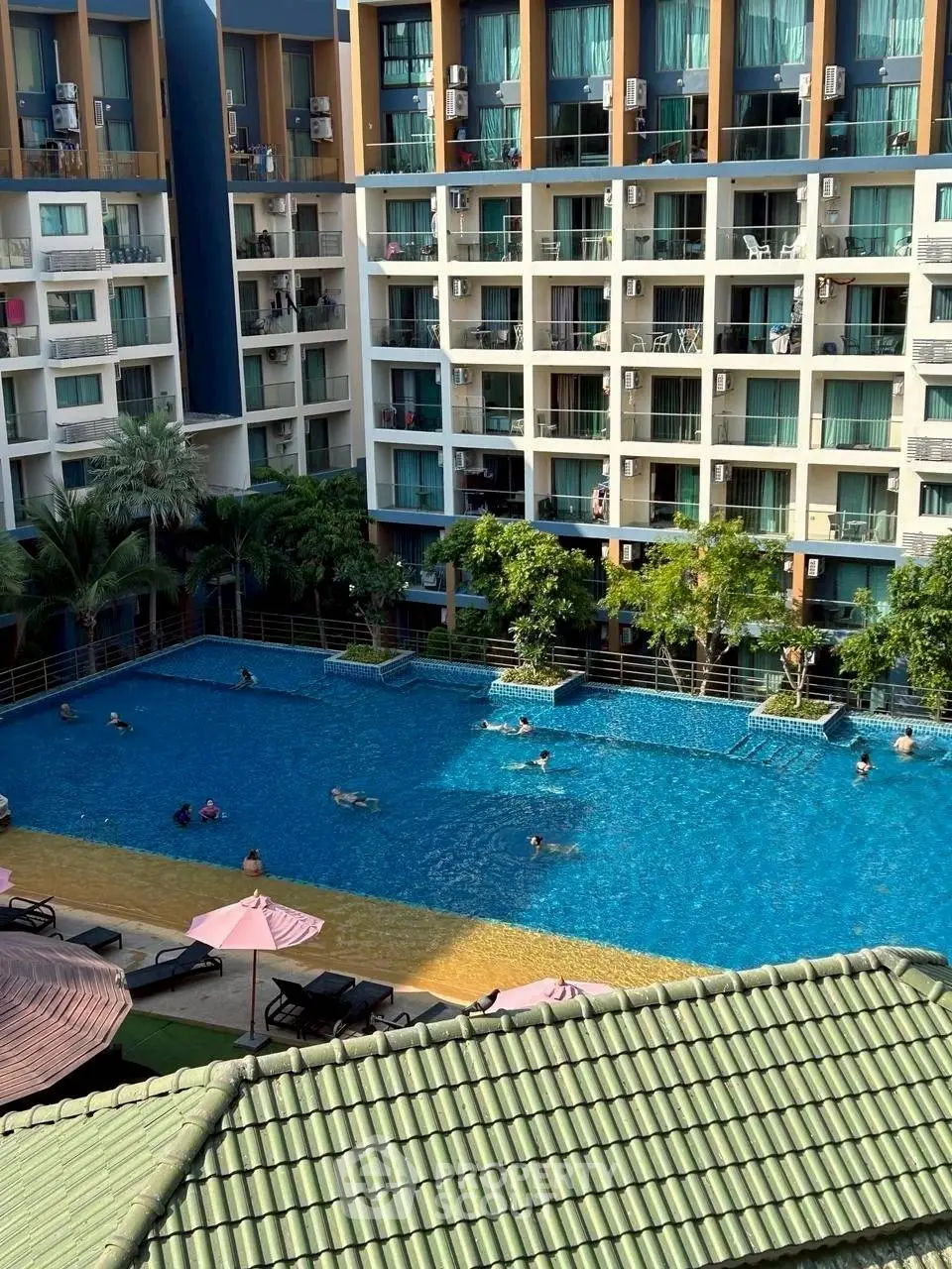 Luxurious apartment complex with a large swimming pool and lush greenery.