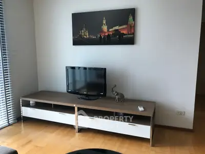 Modern living room with sleek TV stand and wall art, featuring hardwood floors and natural light.