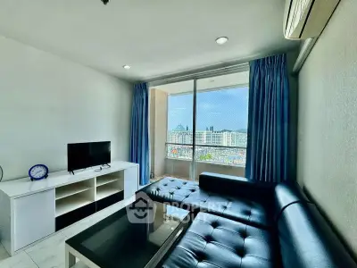 Modern living room with city view, featuring sleek black sofa and large windows for natural light.