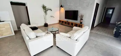 Spacious modern living room with stylish decor and large TV setup, perfect for relaxation.