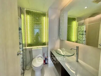 Modern bathroom with glass sink and illuminated mirror in stylish apartment.