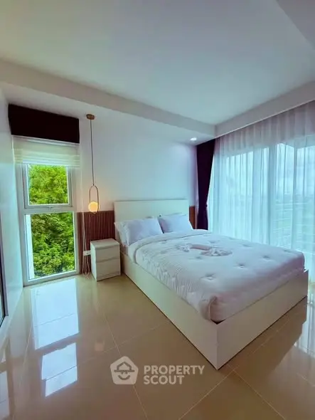 Modern bedroom with large windows and lush green view, featuring elegant decor and natural light.