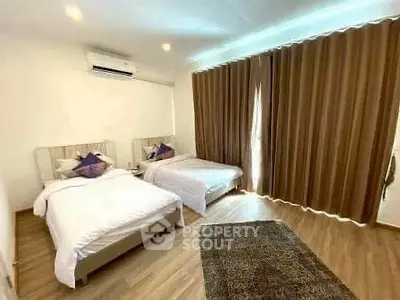 Spacious bedroom with twin beds and elegant curtains in modern apartment.