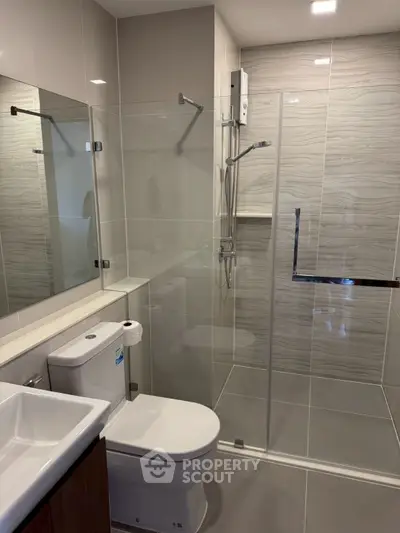 Modern bathroom with glass shower and sleek fixtures in contemporary apartment.