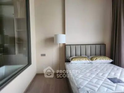 Modern bedroom with elegant decor and large window overlooking bathroom, featuring a cozy bed and stylish floor lamp.