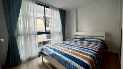 Modern bedroom with large window and stylish bedding in a contemporary apartment.