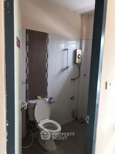 Compact bathroom with modern fixtures and tiled walls, featuring a shower and toilet.