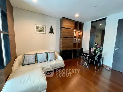 Stylish living room with modern decor and wooden flooring, featuring a cozy sofa and elegant dining area.
