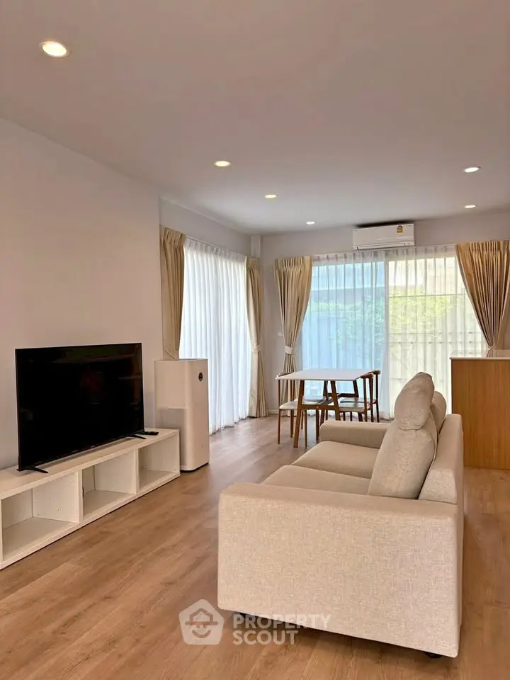 Spacious living room with modern decor, large windows, and natural light in a stylish apartment.