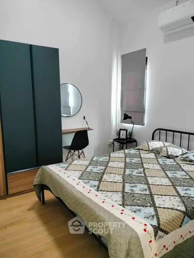 Cozy bedroom with modern decor, featuring a stylish bed, sleek wardrobe, and a compact study area.