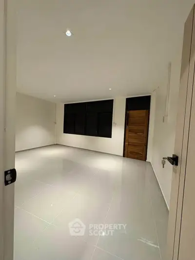Spacious empty room with glossy tiled floor and modern lighting